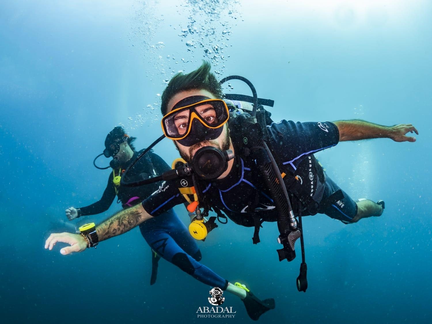Scuba divers gliding through clear blue water on a Koh Tao dive