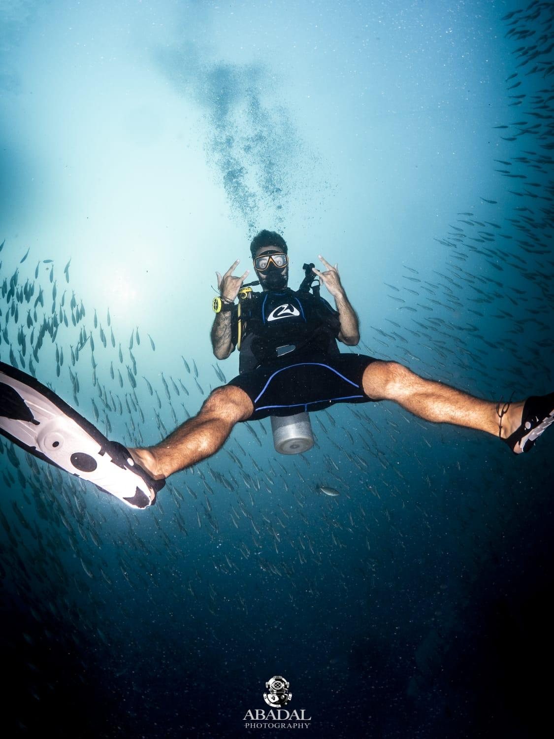 Scuba diver among a swirling school of fish off Koh Tao