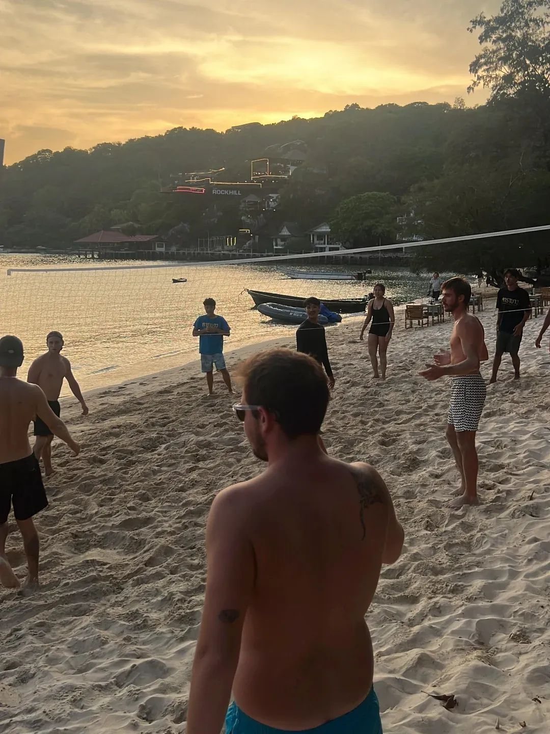 Guests playing beach volleyball at sunset on Chalok Bay outside Carabao Diving Resort